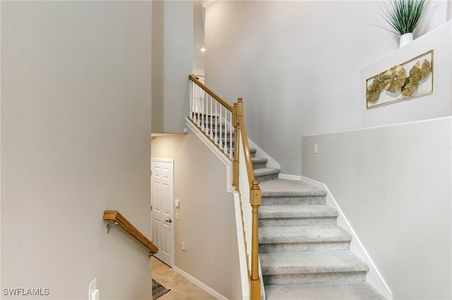 staircase featuring carpet floors and a towering ceiling