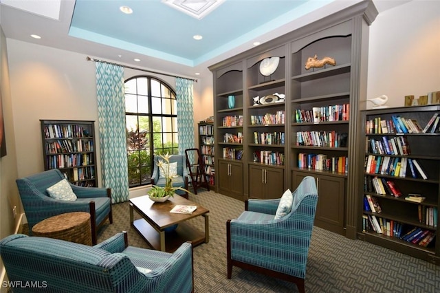 sitting room with a raised ceiling and carpet floors