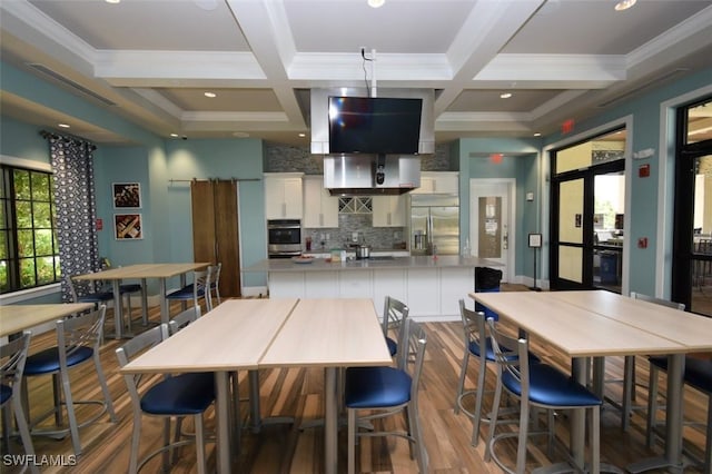 dining space with beamed ceiling, coffered ceiling, crown molding, and light wood-type flooring