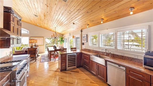 kitchen with sink, light hardwood / wood-style flooring, stainless steel appliances, decorative light fixtures, and beverage cooler