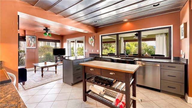 kitchen with gray cabinetry, stainless steel dishwasher, and light tile patterned floors