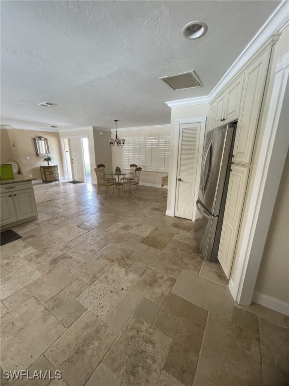 kitchen with cream cabinets, stainless steel refrigerator, and a textured ceiling