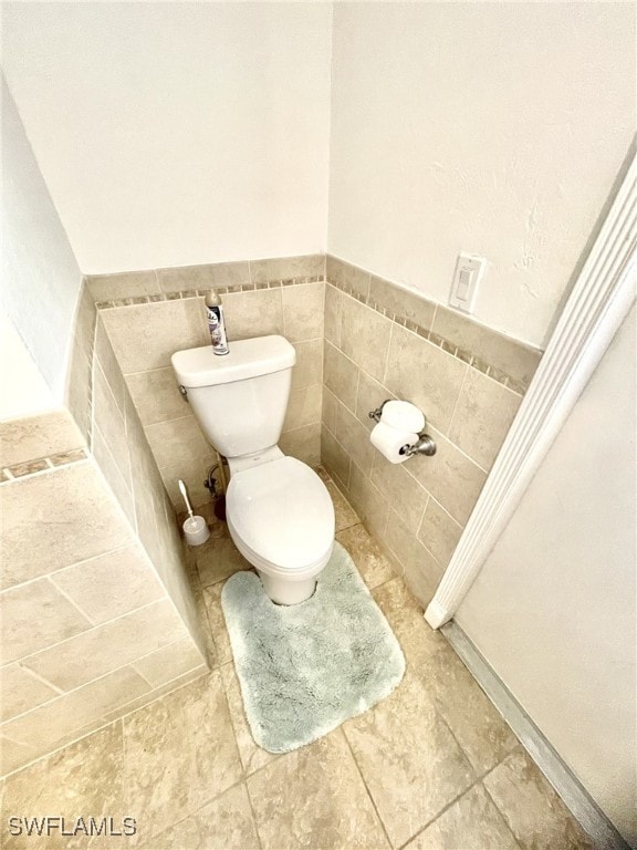 bathroom featuring tile walls and toilet