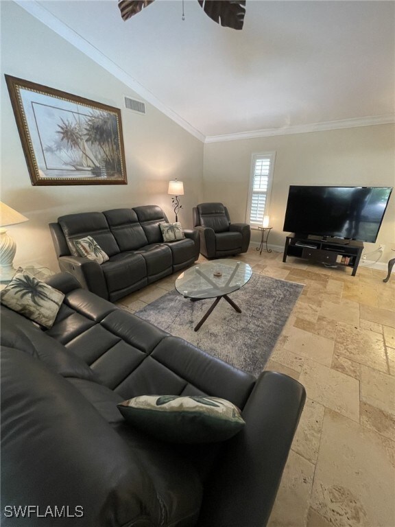 living room featuring ornamental molding and vaulted ceiling