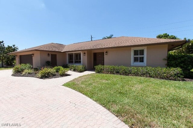 ranch-style house featuring a garage and a front lawn