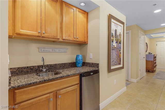 kitchen featuring stainless steel dishwasher, sink, dark stone countertops, and light tile patterned flooring