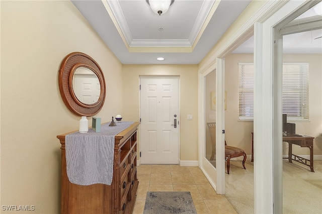 doorway with crown molding, a raised ceiling, and light tile patterned floors