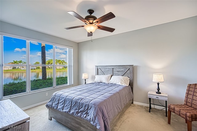 carpeted bedroom with a water view and ceiling fan