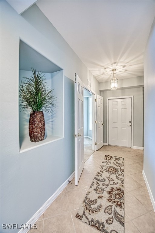 hallway featuring light tile patterned floors and a chandelier