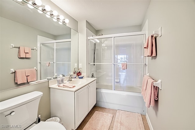 full bathroom featuring enclosed tub / shower combo, vanity, and toilet