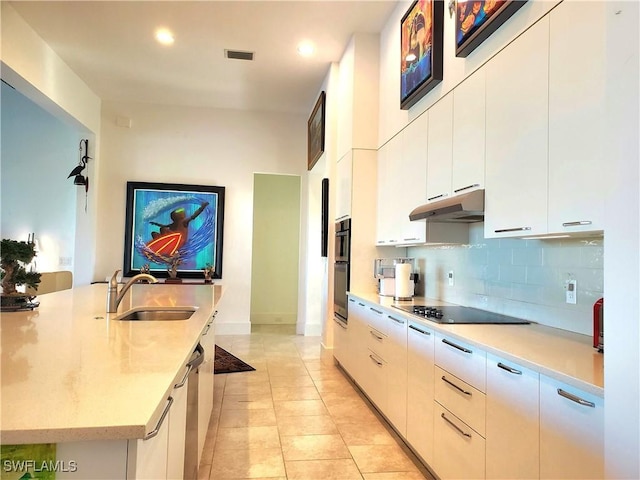 kitchen featuring visible vents, a sink, under cabinet range hood, black appliances, and backsplash