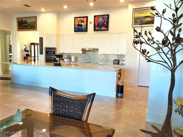 kitchen featuring visible vents, backsplash, wall oven, white cabinetry, and under cabinet range hood