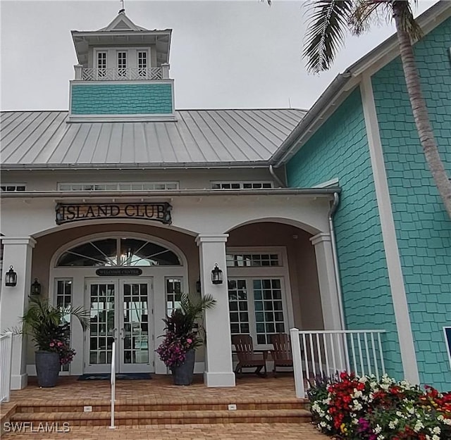 entrance to property with french doors, covered porch, metal roof, and a standing seam roof