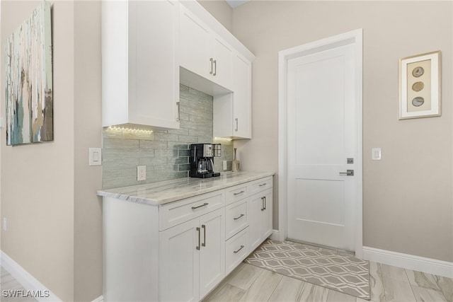 kitchen with white cabinetry, light stone counters, and decorative backsplash