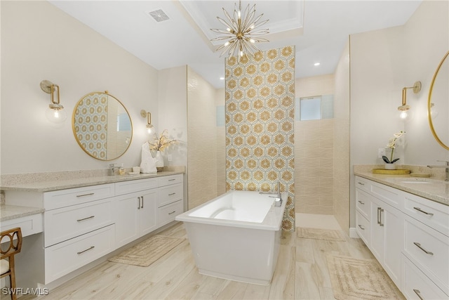 bathroom featuring independent shower and bath, vanity, and a notable chandelier