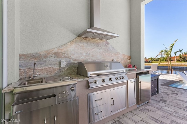 view of patio / terrace featuring area for grilling, sink, a water view, and exterior kitchen