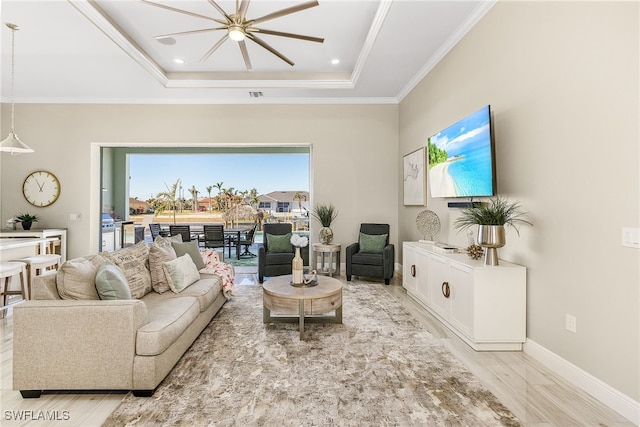 living room with crown molding, a tray ceiling, and light hardwood / wood-style floors