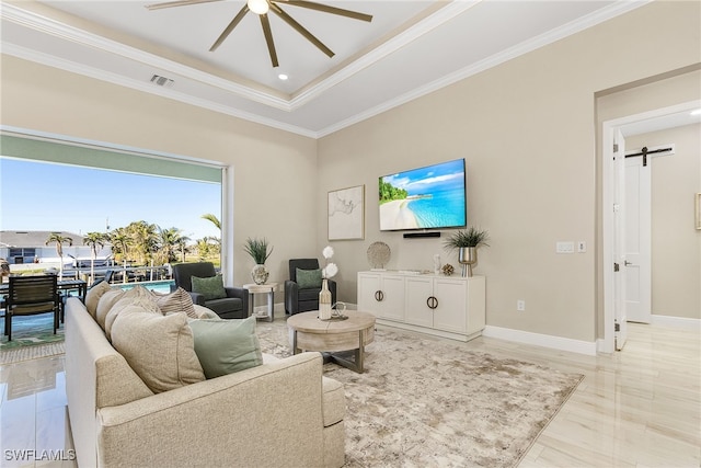 living room with ornamental molding, a barn door, ceiling fan, and a tray ceiling