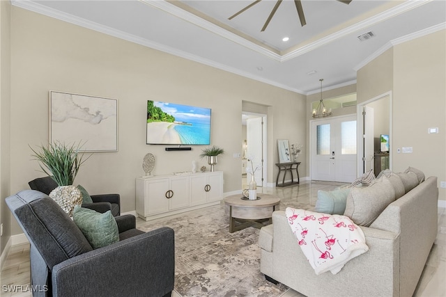 living room with a tray ceiling, crown molding, and ceiling fan with notable chandelier