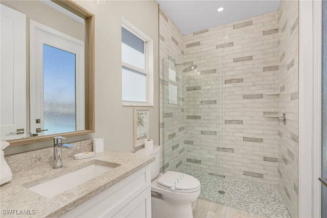 bathroom featuring vanity, toilet, and a tile shower