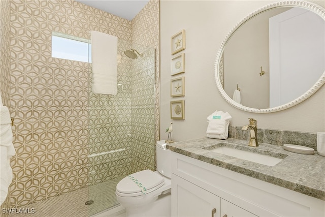 bathroom featuring vanity, toilet, and a tile shower