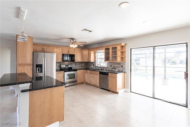 kitchen with a breakfast bar area, dark stone countertops, appliances with stainless steel finishes, pendant lighting, and decorative backsplash