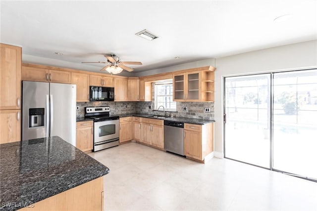 kitchen featuring appliances with stainless steel finishes, sink, dark stone countertops, decorative backsplash, and ceiling fan