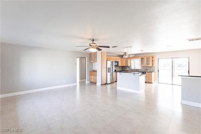 kitchen with sink, tasteful backsplash, decorative light fixtures, a center island, and stainless steel fridge