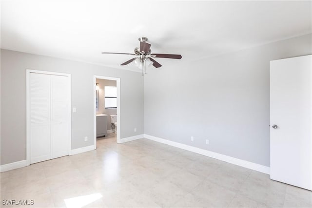 unfurnished bedroom with ceiling fan, ensuite bathroom, and a closet