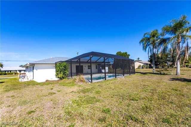 rear view of house with a patio, a yard, and glass enclosure