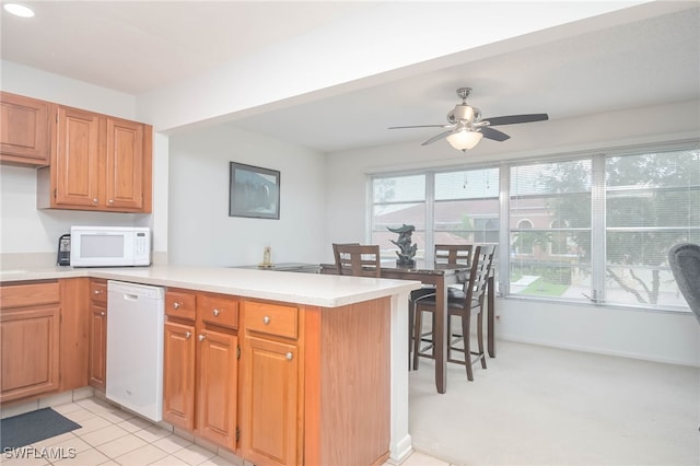 kitchen featuring light tile patterned floors, white appliances, kitchen peninsula, and ceiling fan