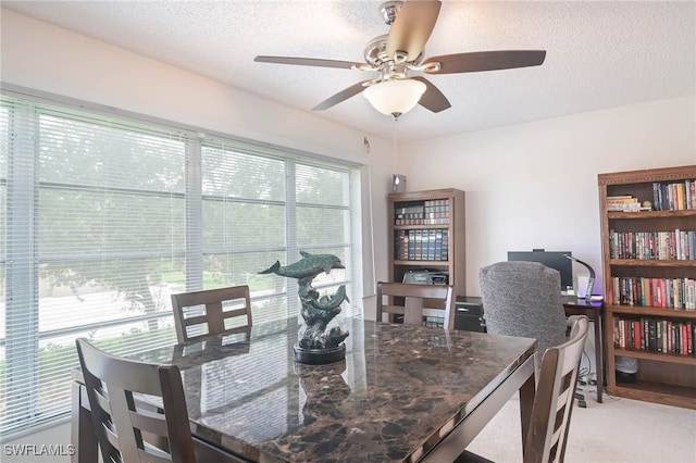 dining space with ceiling fan, light carpet, and a textured ceiling