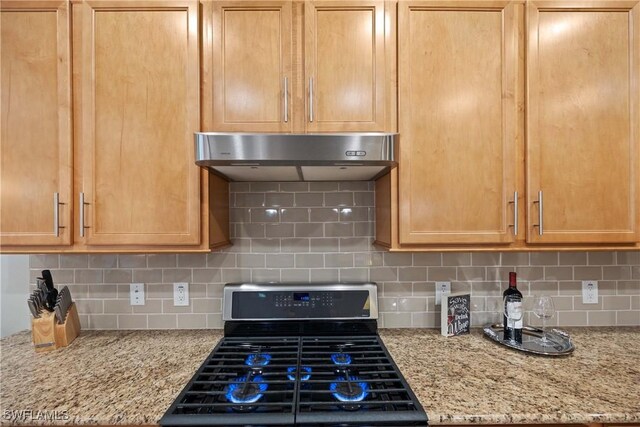 kitchen with gas range, light stone countertops, backsplash, and light brown cabinetry