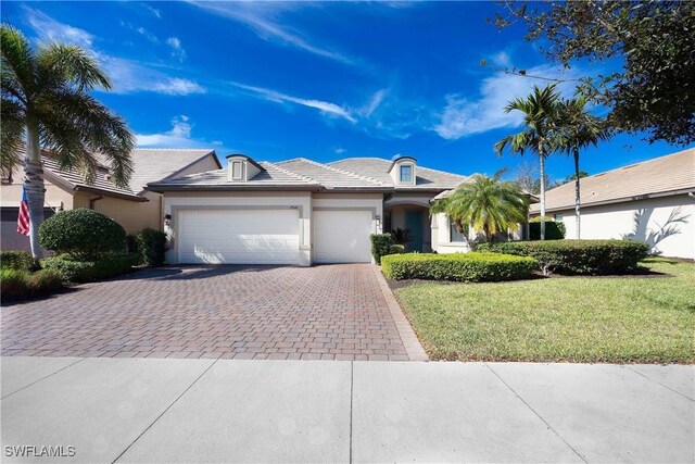 7045 Live Oak Dr, Naples, FL 34114 - single story home featuring decorative driveway, a garage, stucco siding, and a front lawn