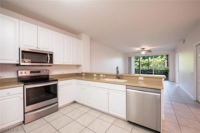 kitchen featuring sink, light tile patterned floors, kitchen peninsula, stainless steel appliances, and white cabinets