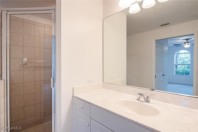 bathroom with vanity, ceiling fan, a textured ceiling, and a shower with shower door