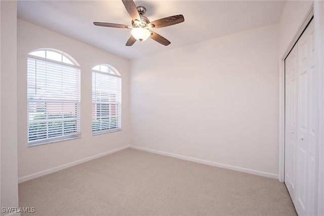 spare room with ceiling fan and light colored carpet