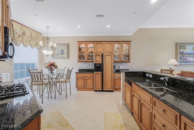 kitchen featuring sink, crown molding, backsplash, decorative light fixtures, and dark stone counters