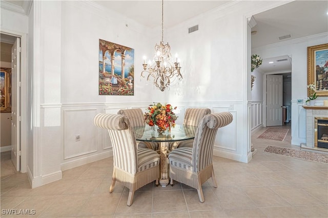 tiled dining space featuring a notable chandelier, crown molding, and a brick fireplace