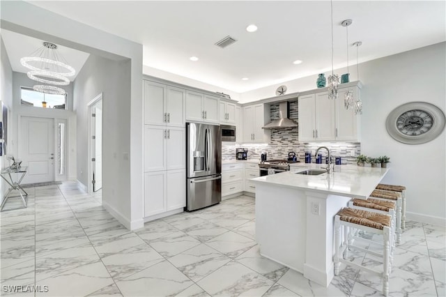 kitchen featuring pendant lighting, sink, wall chimney range hood, and stainless steel appliances