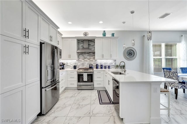 kitchen featuring pendant lighting, sink, stainless steel appliances, a kitchen bar, and wall chimney exhaust hood