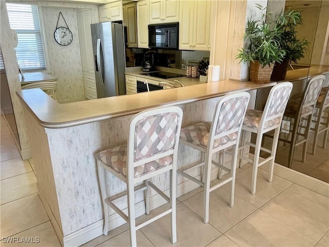 kitchen with a breakfast bar area, kitchen peninsula, and black appliances