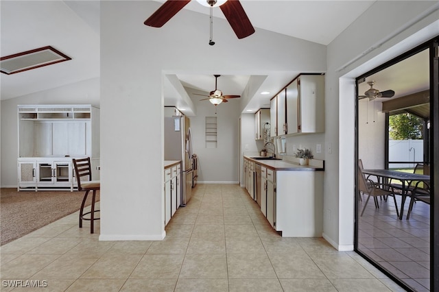 kitchen with lofted ceiling, sink, light tile patterned floors, stainless steel refrigerator, and ceiling fan