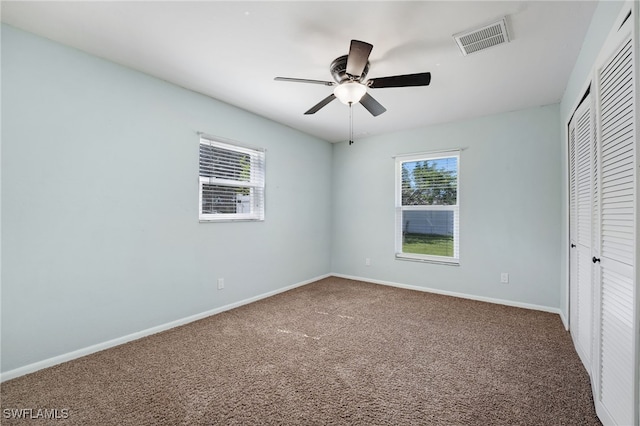 unfurnished bedroom featuring multiple windows, a closet, ceiling fan, and carpet