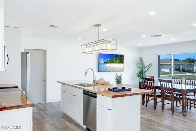 kitchen with sink, butcher block countertops, dishwasher, pendant lighting, and a kitchen island with sink