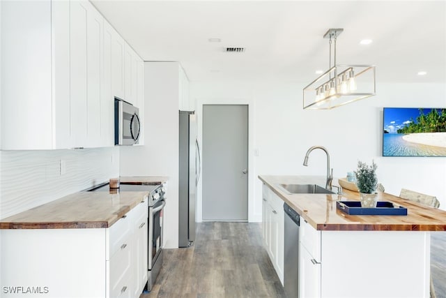 kitchen with butcher block counters, sink, white cabinetry, hanging light fixtures, and appliances with stainless steel finishes