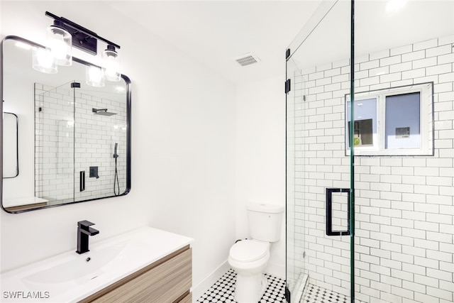 bathroom featuring a shower with door, vanity, tile patterned flooring, and toilet