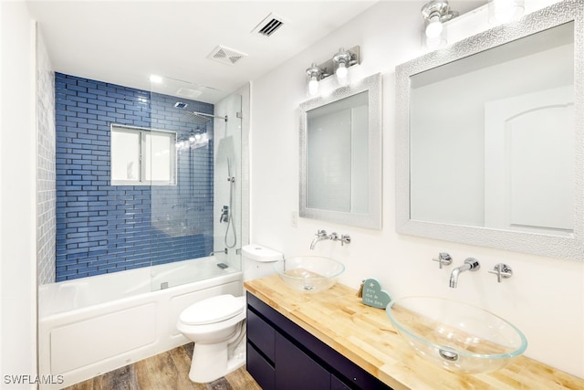 full bathroom featuring tiled shower / bath, wood-type flooring, vanity, and toilet