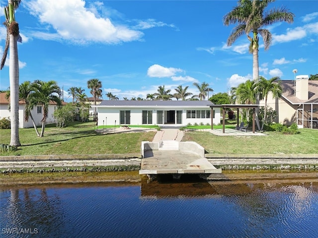 back of property with a water view and a lawn