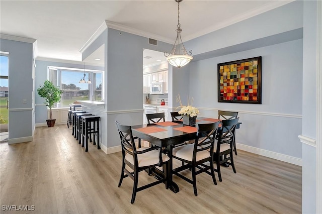 dining room featuring ornamental molding and light hardwood / wood-style floors